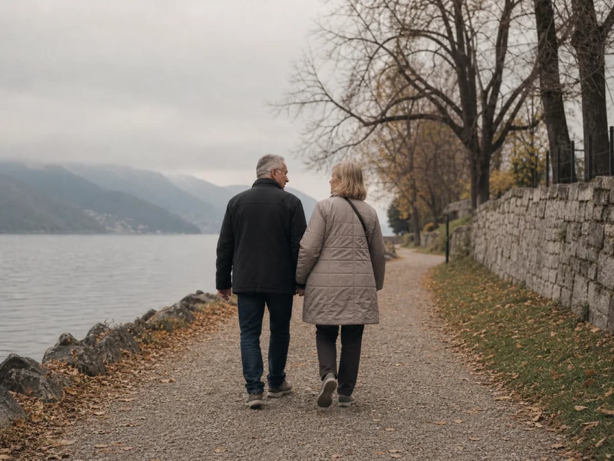 Älteres Paar geht Hand in Hand einen Kiesweg an einem Schweizer See entlang